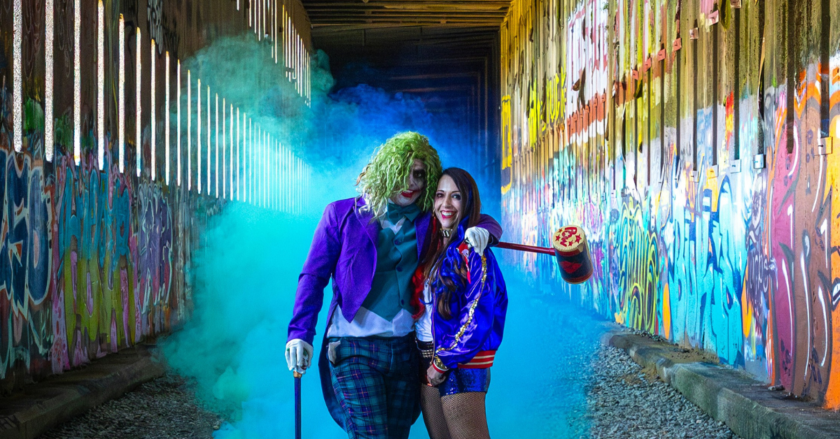 Couple dressed in colorful Halloween costumes holding hands