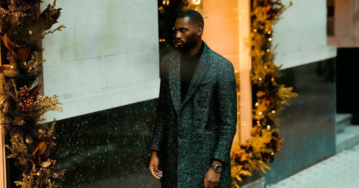 man wearing modern mens outfit with coat standing on city street