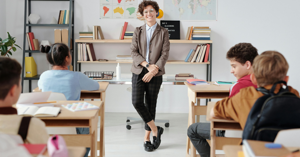 Teacher wearing a professional classroom outfit while interacting with students in a bright and positive classroom environment