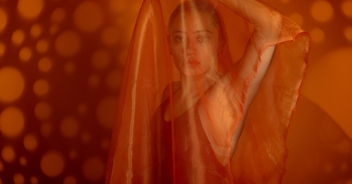 Woman in sheer flowing fabric with soft glowing light representing ethereal style essence