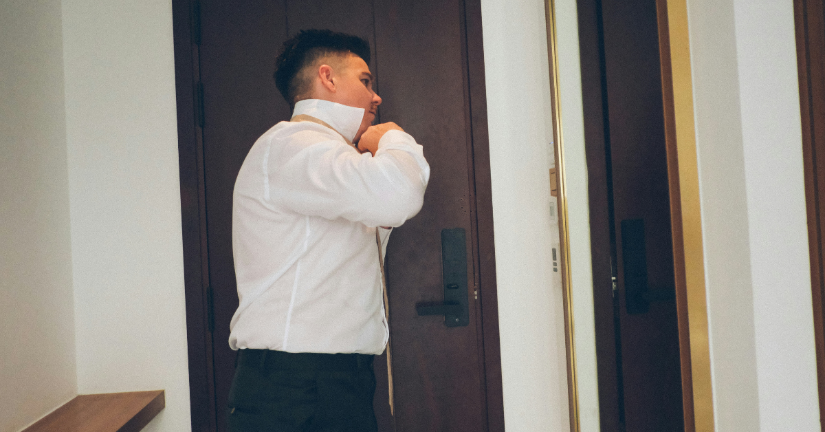 man adjusting shirt collar with collar stays for a crisp look